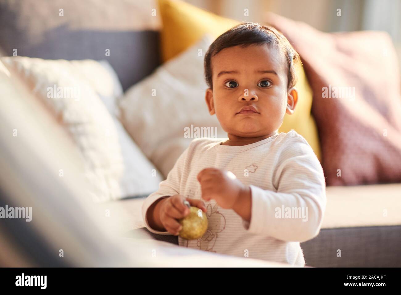 Portrait d'enfant debout près du canapé et holding toy camera et dans les prix à la maison Banque D'Images