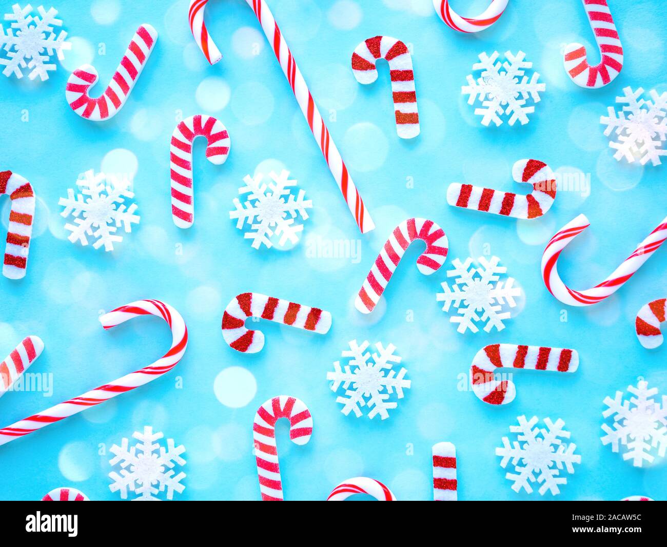 Motif de Noël avec des bonbons et des flocons sur fond bleu lumineux avec effet bokeh. Mise à plat Banque D'Images Motif de Noël avec des bonbons et des flocons sur fond bleu lumineux avec effet bokeh. Mise à plat Banque D'Images