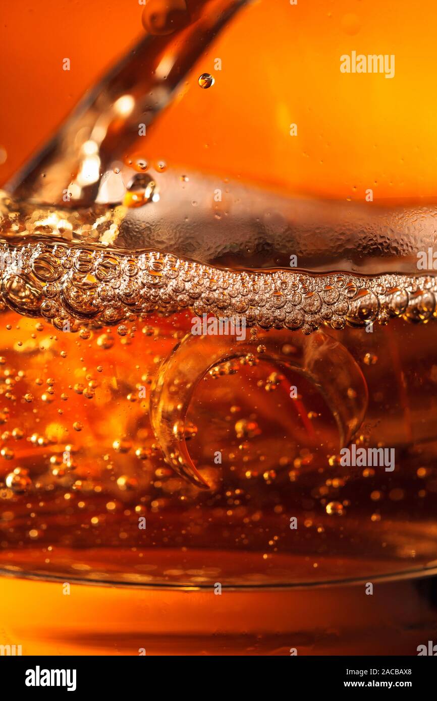 Le whisky est versé dans un verre avec de la glace. Un plan macro. Banque D'Images