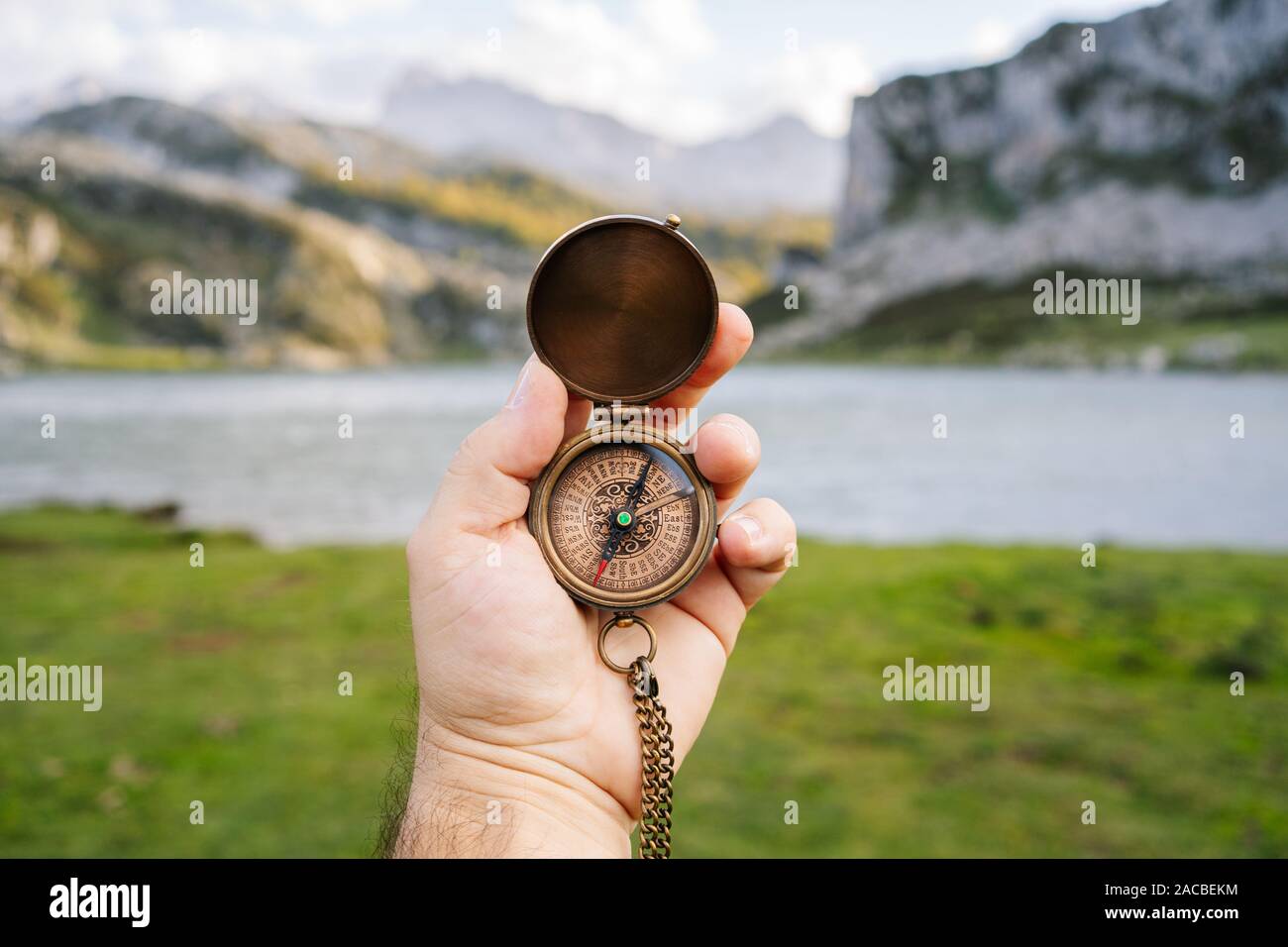Une main tient une boussole dans un paysage de montagne et lac Banque D'Images