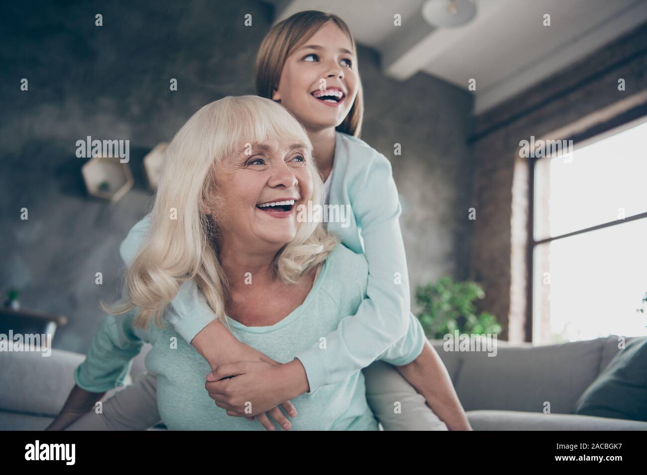 Low angle view photo de deux meilleurs amis personnes âgées de mignons petits granny piggyback hug fille petit-enfant jeu drôle de jeu passer week-end ensemble chambre Banque D'Images