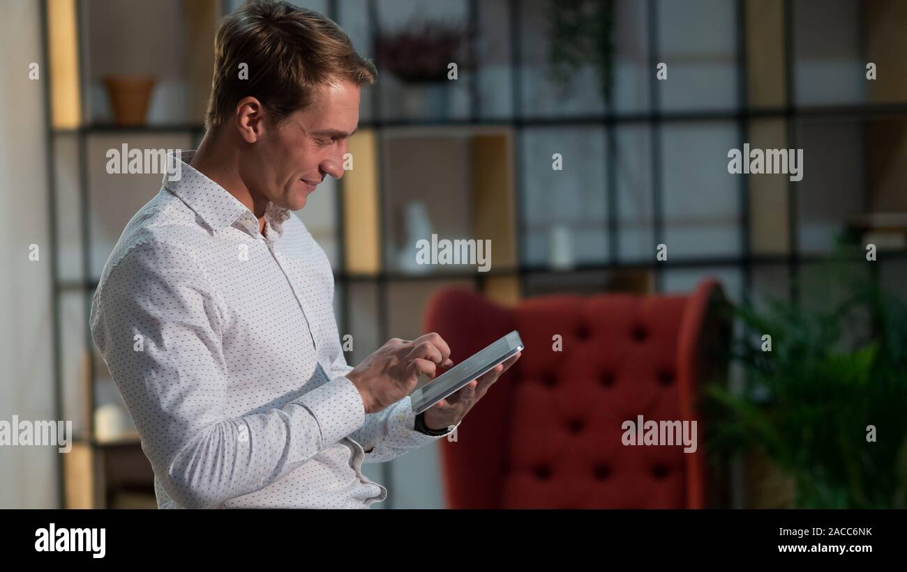 Utilisation d'applications et de technologies modernes pour le travail et la communication. Portrait d'un jeune homme positif et confiant dans une chemise blanche classique. Banque D'Images