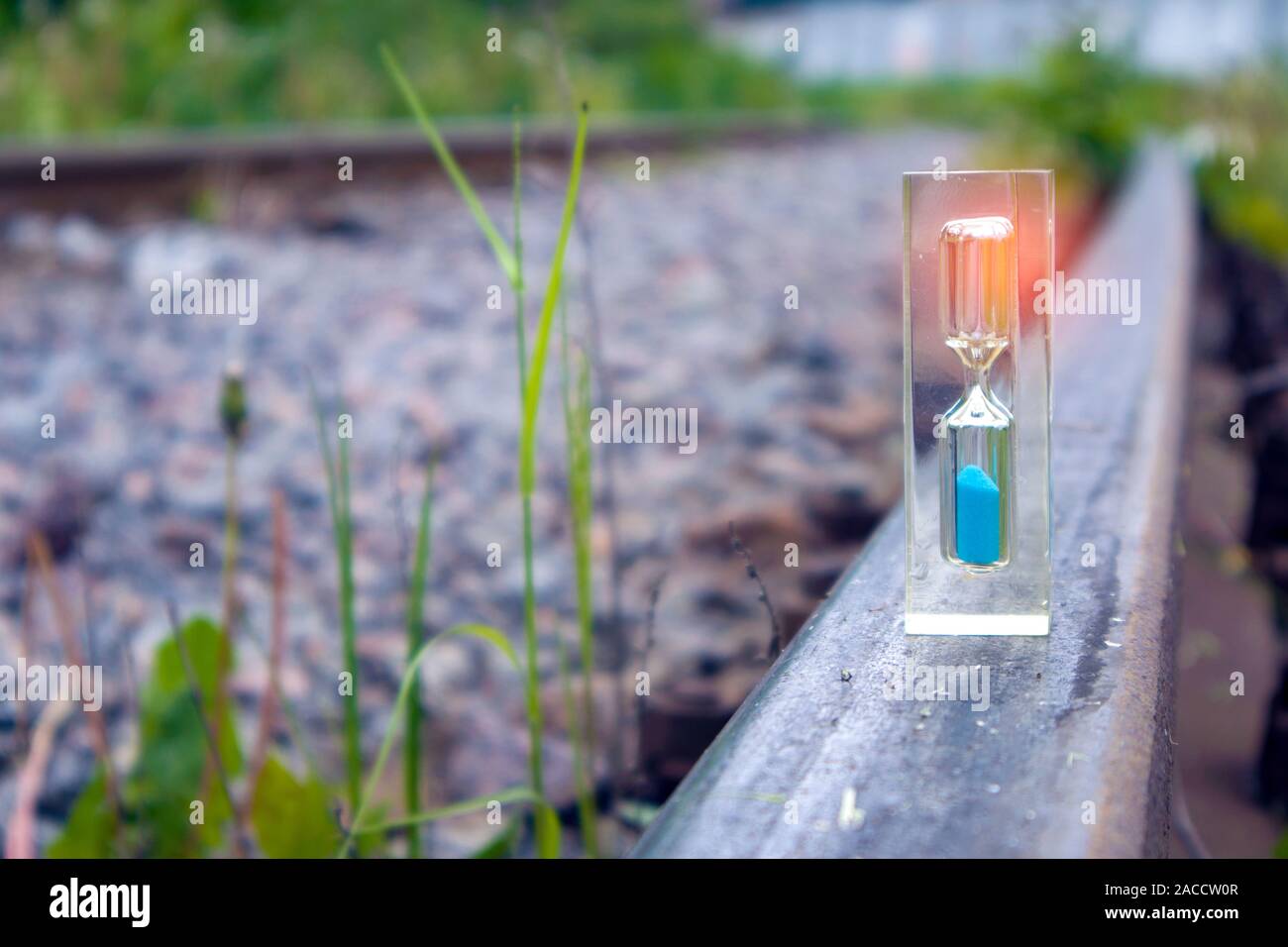Hourglass transparent avec sable bleu l'article sur l'ancien chemin de fer rouillé avec effet de lumière, l'heure concept Banque D'Images