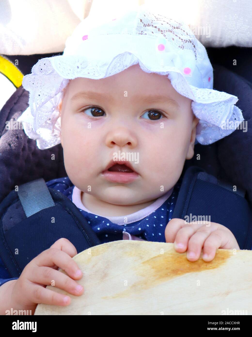 Pensive Bébé Adorable fille vêtue d'un capuchon avec volants à l'extérieur dans baby carriage Banque D'Images