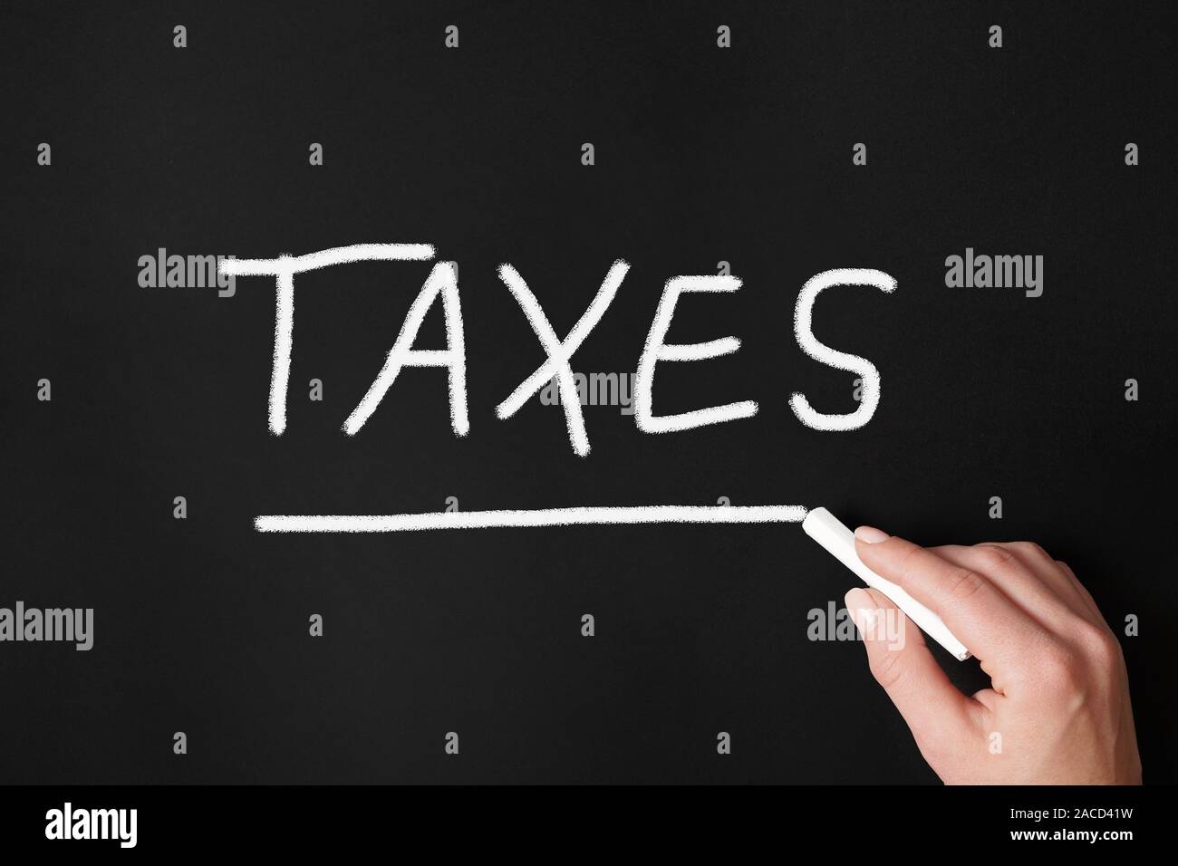 La main féminine mot impôts avec la craie sur tableau noir ou tableau noir - concept fiscal Banque D'Images
