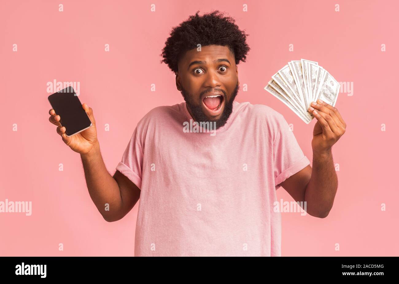Ravis guy holding phone et montrant tas d'argent Banque D'Images