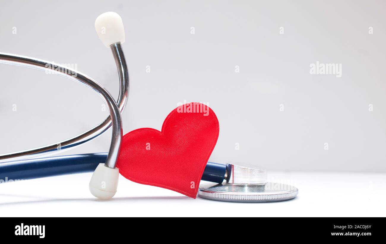 Concept de soins de santé : un coeur en tissu rouge à l'intérieur d'un stéthoscope sur tableau blanc Banque D'Images