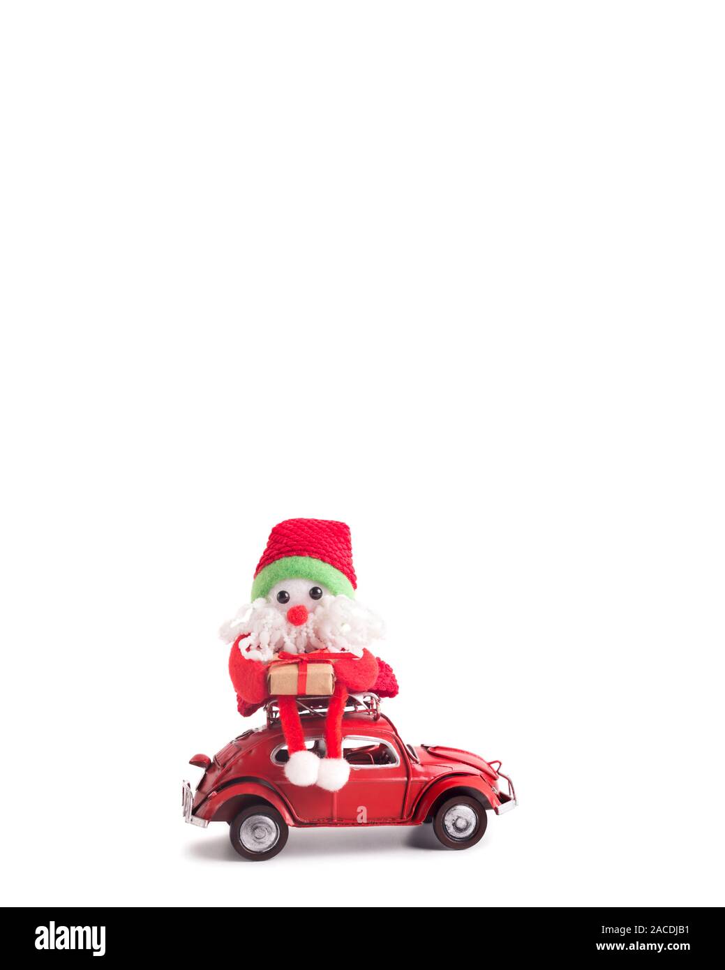 Toy Santa assis sur le toit de voiture rétro rouge sur blanc Volkswagen Beetle Banque D'Images