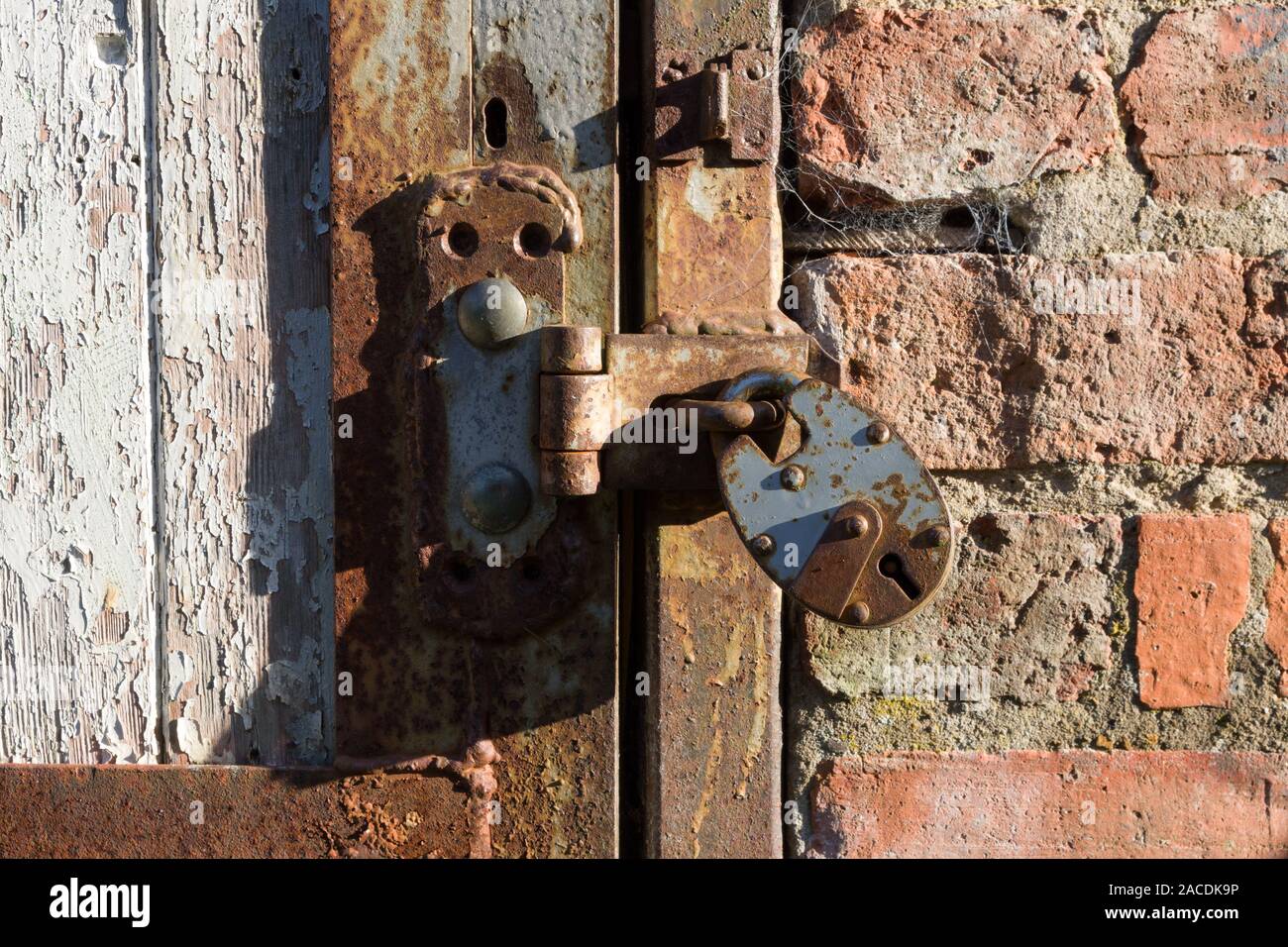 Close up d'un cadenas rouillé et sur un hasp weathered wood porte, UK Banque D'Images
