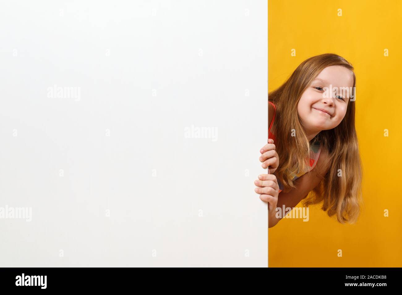 Happy happy cute little girl holding a blank banner espace blanc sur fond jaune. Banque D'Images