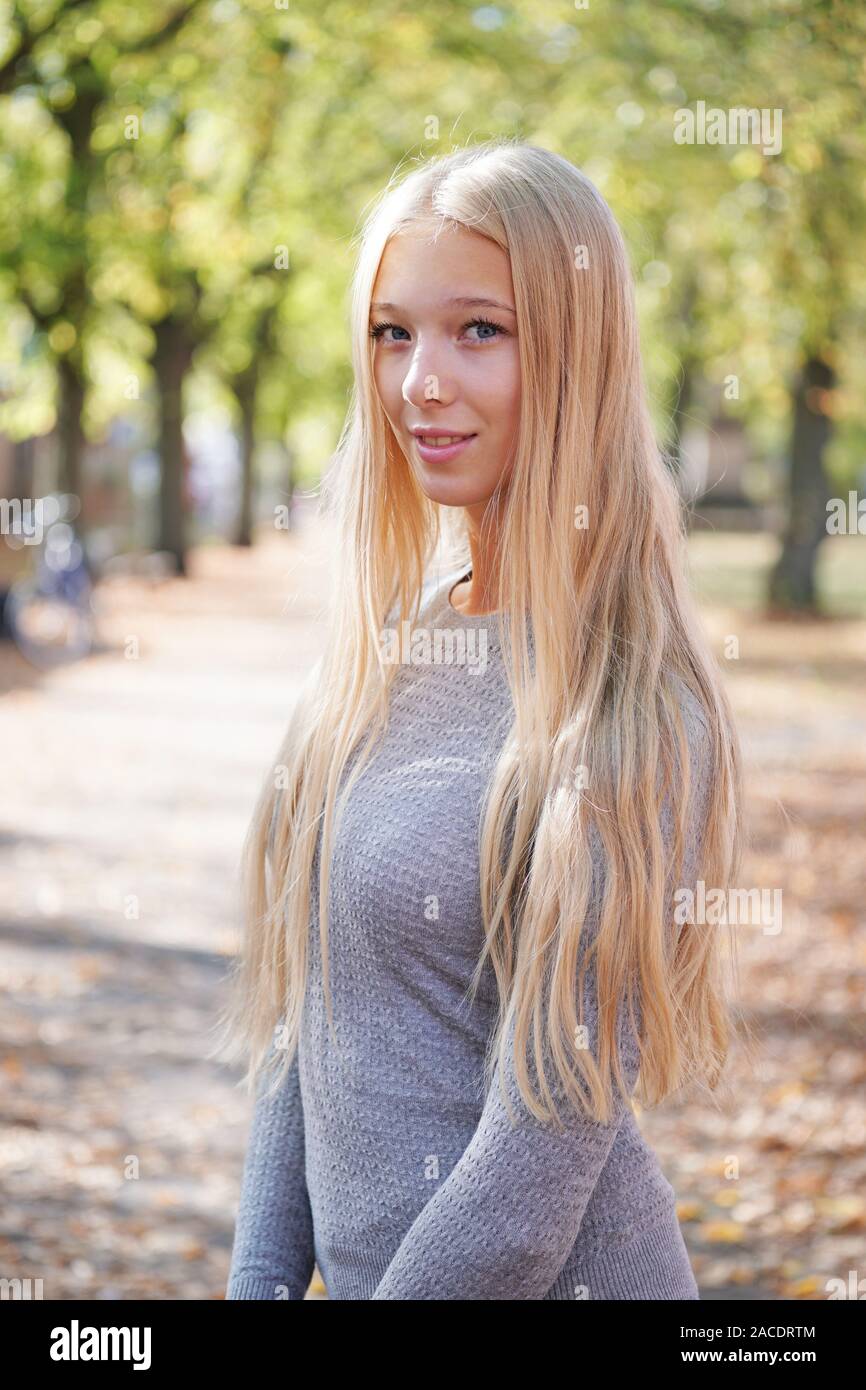 Portrait of teenage girl avec de longs cheveux blonds profiter journée ensoleillée à l'extérieur Banque D'Images