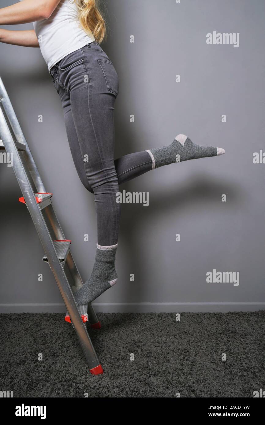 Femme méconnaissable de l'escalade et équilibre sur échelle en chaussettes - amélioration de l'habitat ou de bricolage à la maison concept tendance Banque D'Images