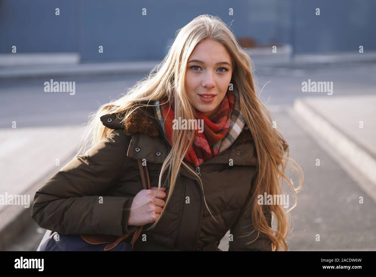 Street style franc portrait of teenage girl waiting at bus stop lors d'une journée ensoleillée en hiver Banque D'Images