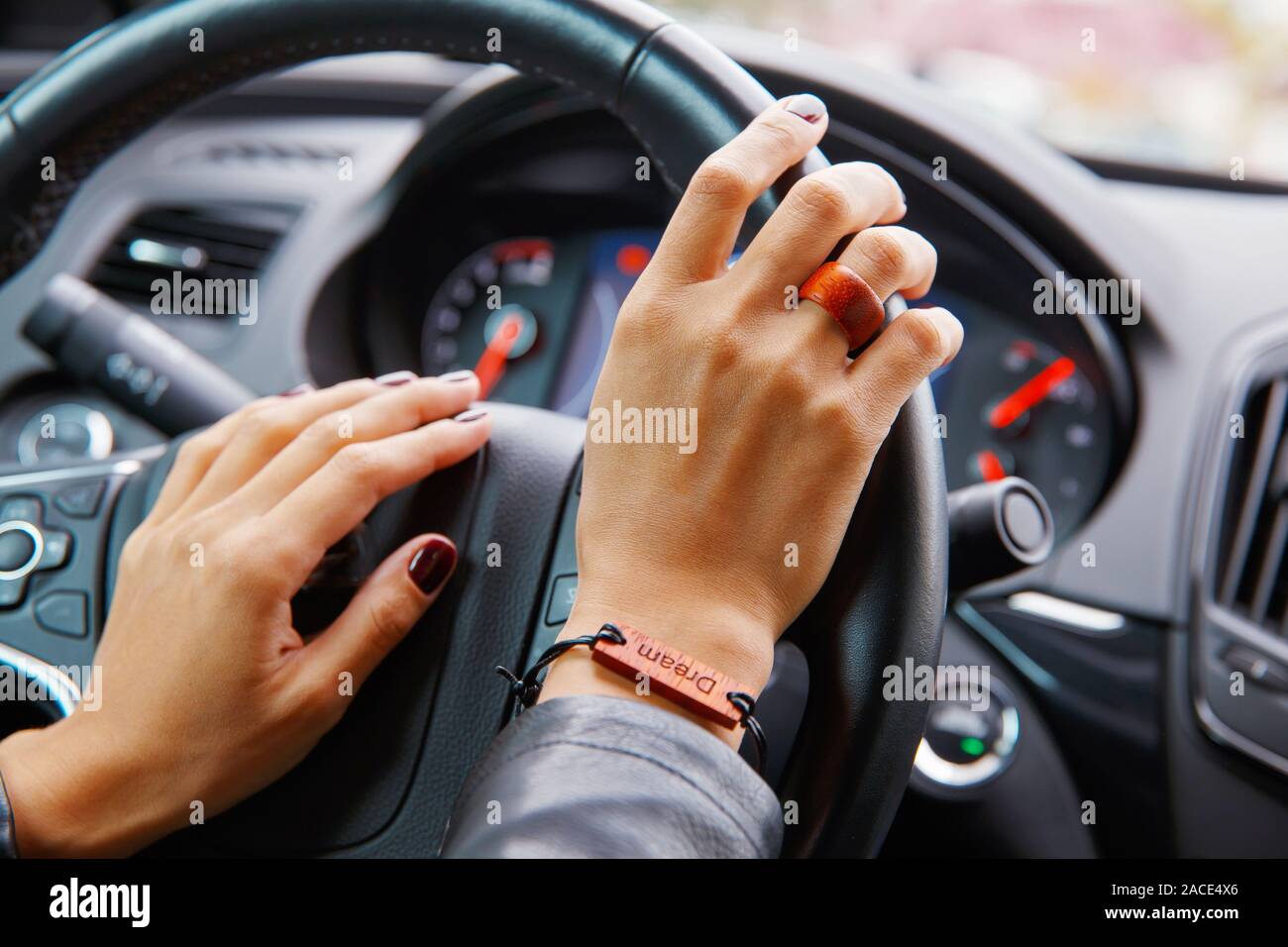 Concept de prise de vue : girl s mains sur le volant d'une voiture, un bracelet avec l'inscription dream sur sa main. Banque D'Images