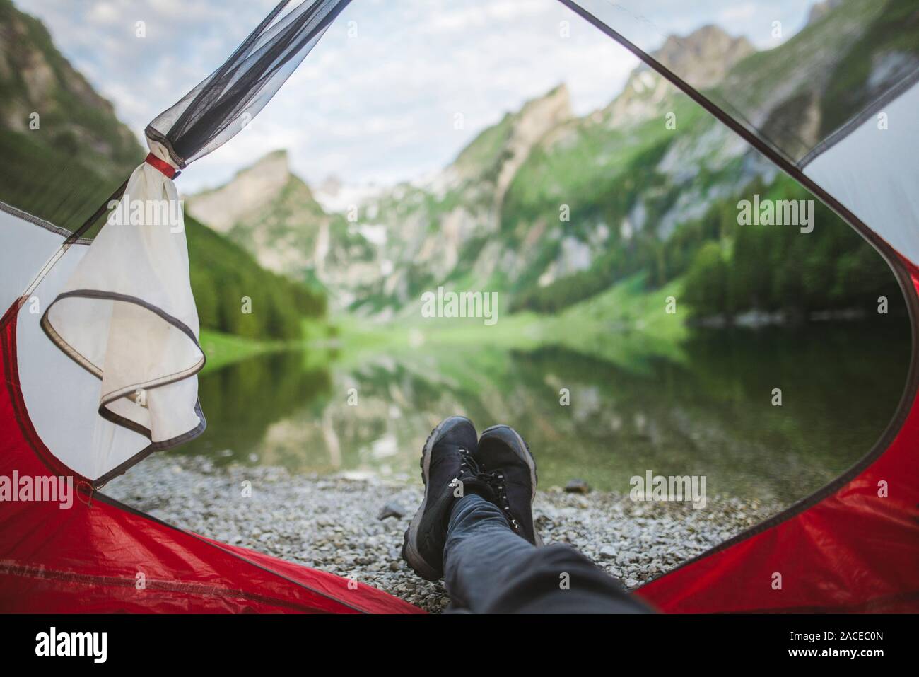 Les pieds de la femme sortent de la tente par le lac Seealpsee dans les Alpes d'Appenzell, en Suisse Banque D'Images