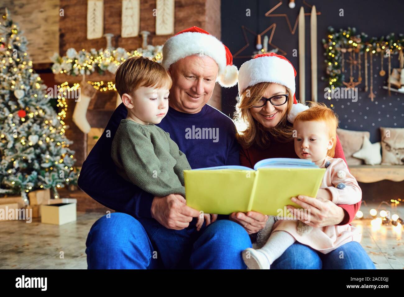 Les grands-parents lire un livre aux enfants à Noël Banque D'Images