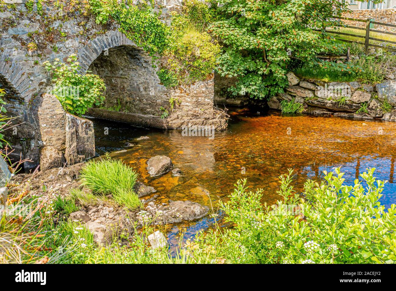 Owenglin ou rivière Owenglen avec le vieux pont Ardbear avec de l'eau transparente et entourée de végétation verte, ensoleillée et journée calme à Clifden Banque D'Images