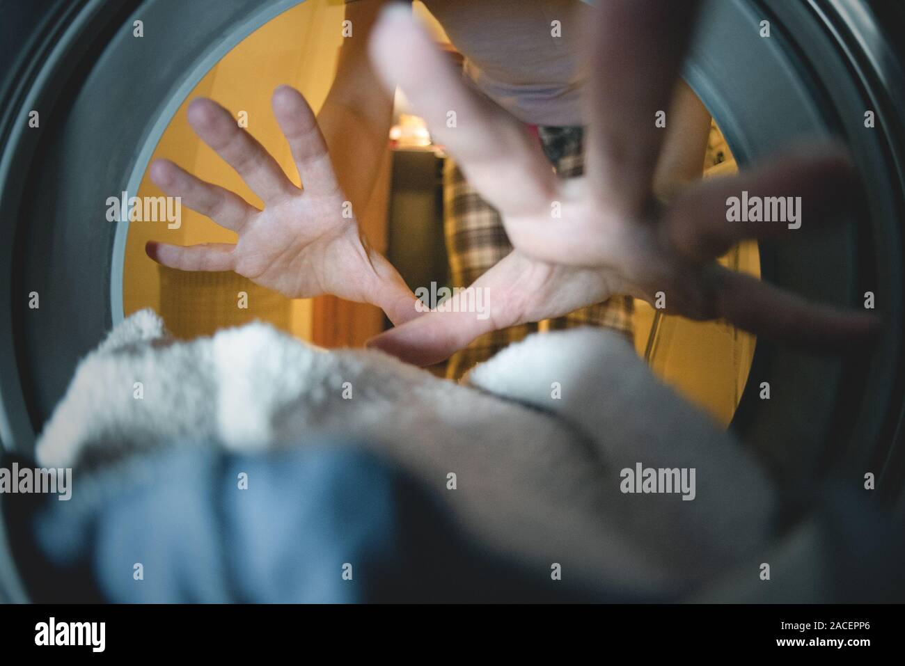 Image floue de femme main et vêtements sales dans la machine à laver de près. Vue depuis un tambour de lave-glace. Concept de blanchisserie. Vue Fisheye. Banque D'Images