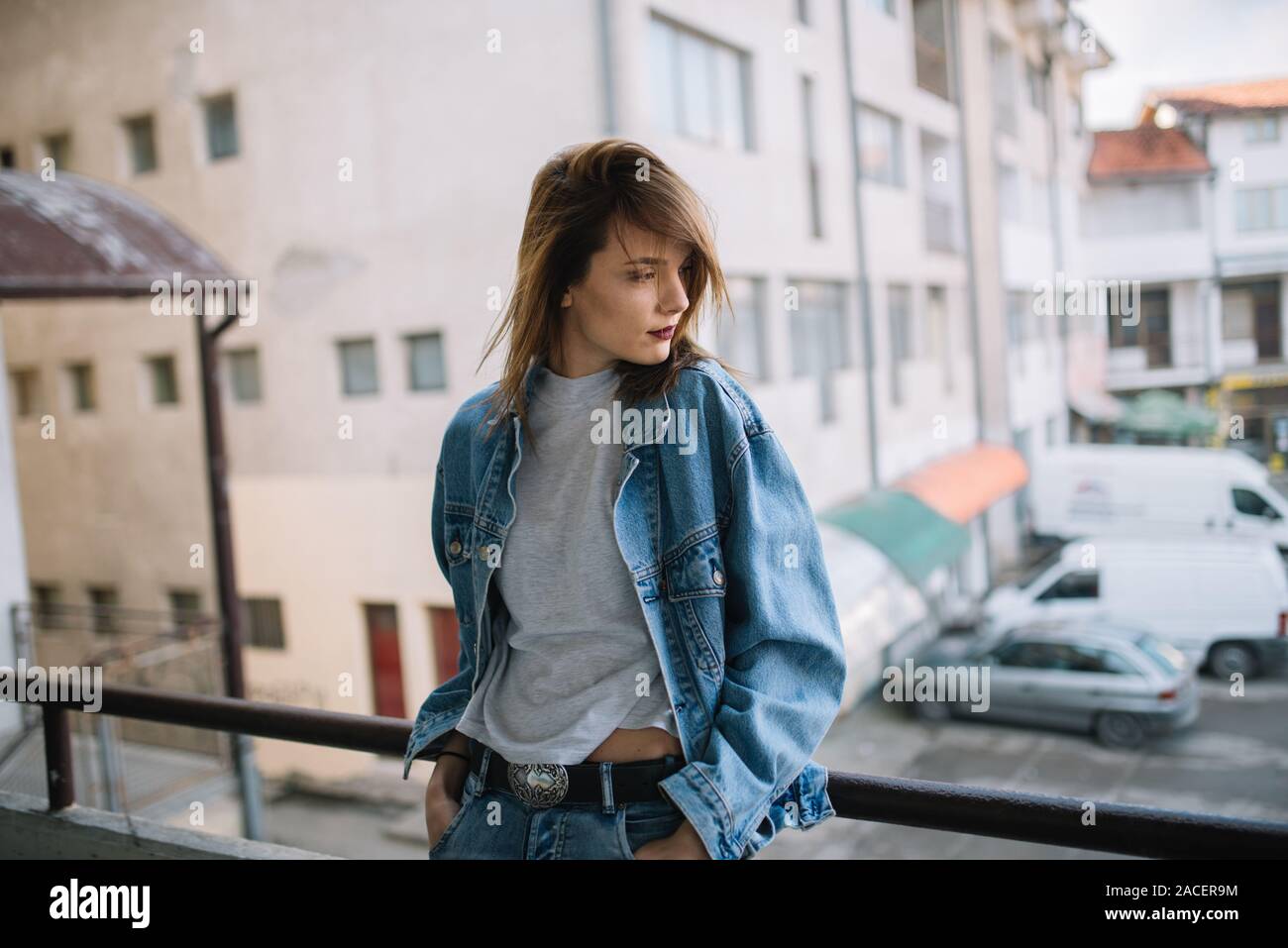 Hipster girl appuyée contre une balustrade avec des capacités sur l'arrière-plan Banque D'Images