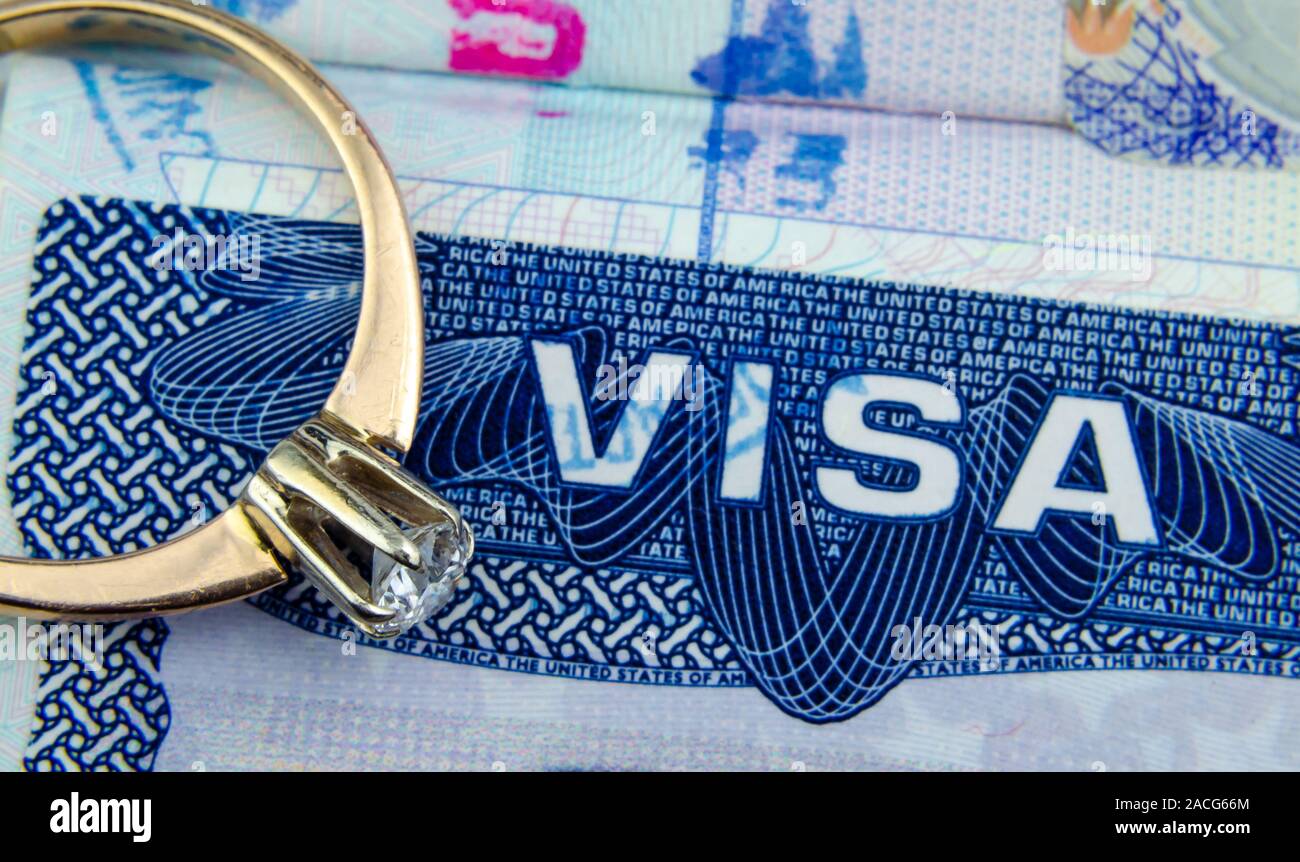 Macro photo d'entre nous la vignette visa d'entrée dans un passeport et un engagement bague à diamant. Photo conceptuelle de l'immigration, de l'époux / partenaire / visa de fiancée. Banque D'Images