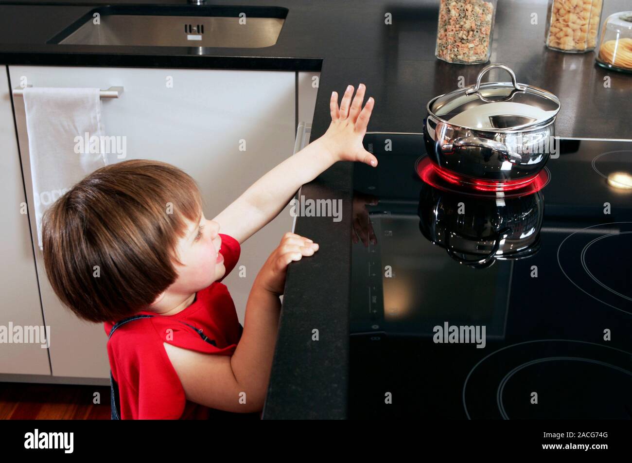 La sécurité à domicile. Jeune fille pour atteindre une casserole d'eau  bouillante de cuisson sur un four chaud Photo Stock - Alamy