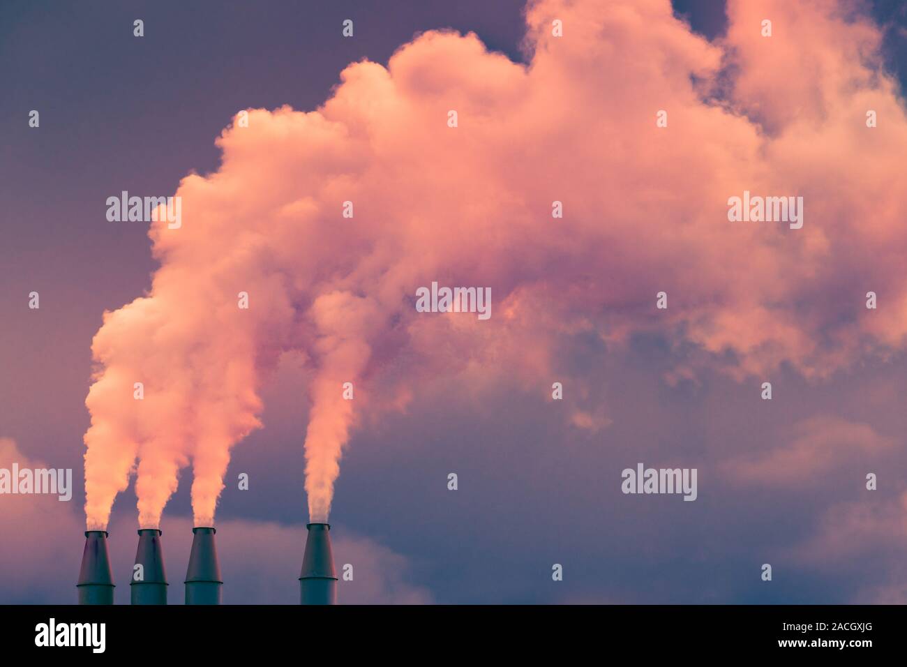 La fumée et la vapeur s'élevant dans l'air à partir de piles de la centrale ; les nuages sombres de l'arrière-plan ; concept pour la pollution de l'environnement et le changement climatique Banque D'Images