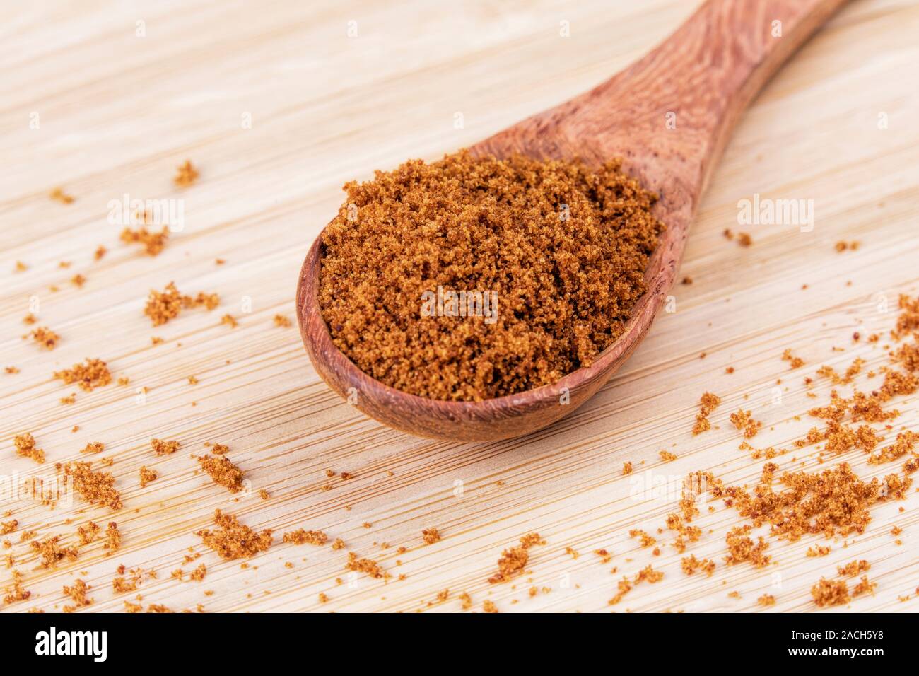 Cuillère en bois plein de sucre brun foncé sur un fond de bois Banque D'Images
