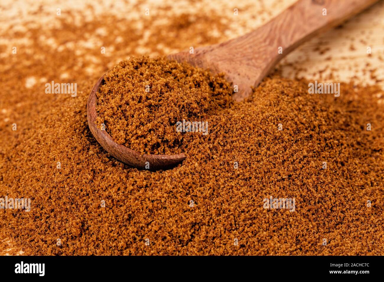 Cuillère en bois plein de sucre brun foncé sur un fond de bois Banque D'Images