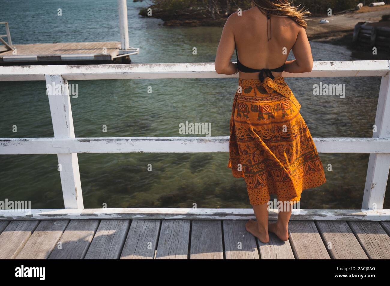 À partir de l'eau regardant femme Boho jetée en bois en Australie Banque D'Images