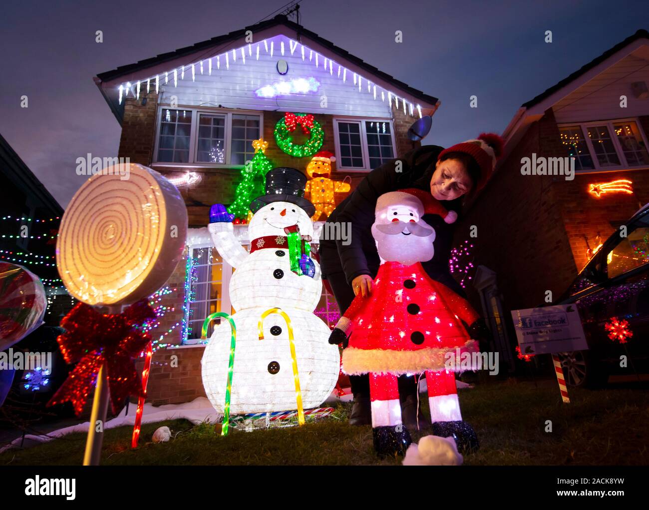 Karen Brown met la pêche à la touche d'affichage de Noël sur Stone Brick Lane à Rothwell, Yorkshire, comme les maisons de la rue sont éclairés par les lumières de Noël lors d'un événement qui est devenu connu comme le Stone Brick Lights. Banque D'Images