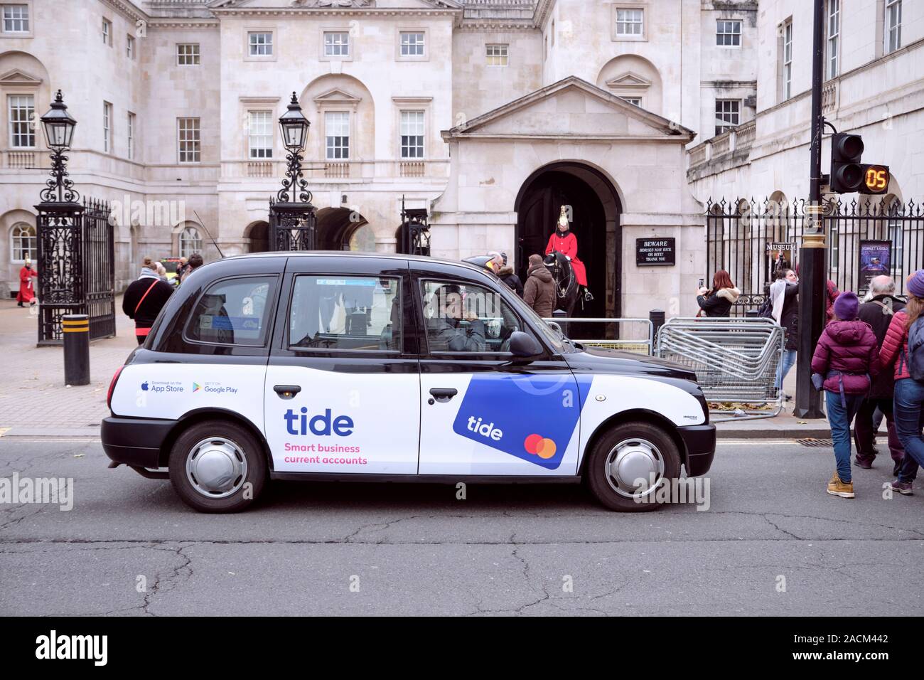 London taxi noir, avec la publicité du compte courant de marée, s'est arrêté à passage pour piétons en face du poste de garde royale. Londres, Royaume-Uni, le 21 novembre 2019 Banque D'Images