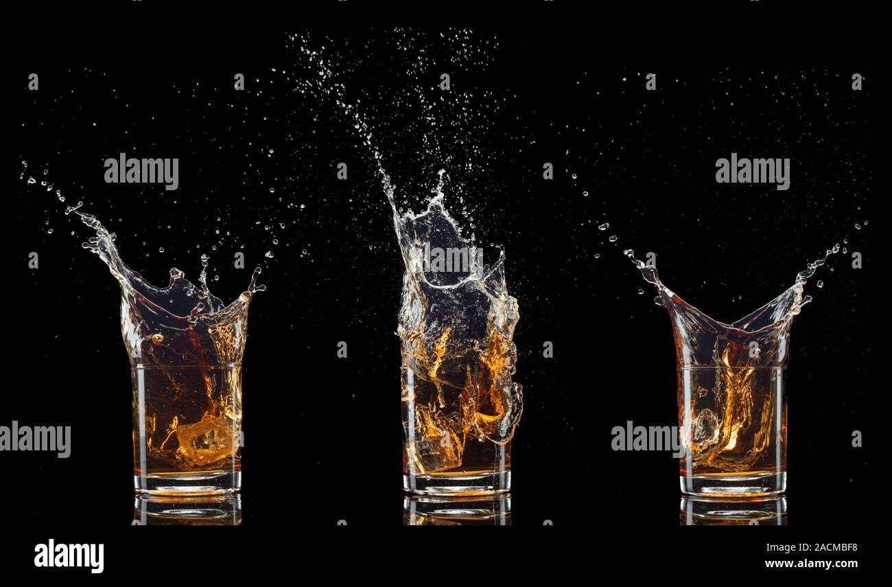 Verres de whisky avec splash, isolé sur fond noir Banque D'Images