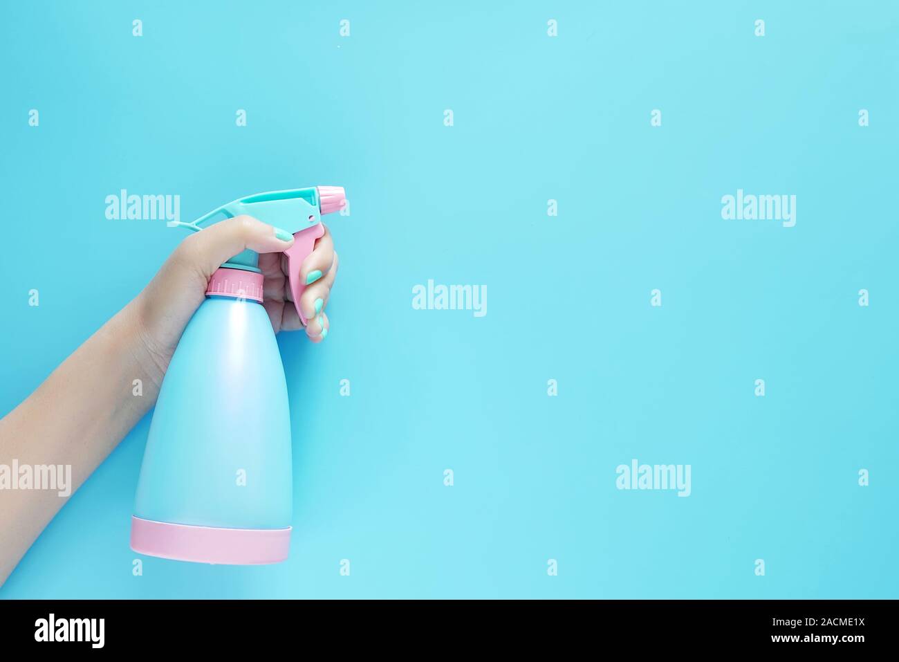 Woman hand holding spray de nettoyage détergent bleu bouteille plastique isolé sur fond bleu avec copie espace pour texte ou logo Banque D'Images