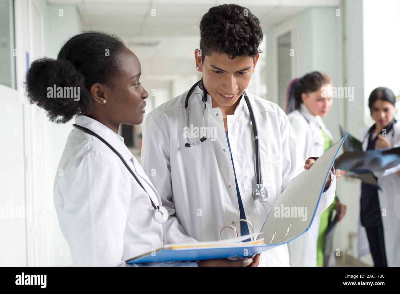 Portrait de médecins, de race mixte. Une fille noire, avec un mec mexicain, en blouse blanche, avec les stéthoscopes, tient des documents médicaux, une consultation, une Banque D'Images