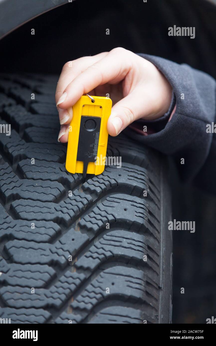 Femme de la bande de roulement des pneus mesures un pneu de voiture Banque D'Images