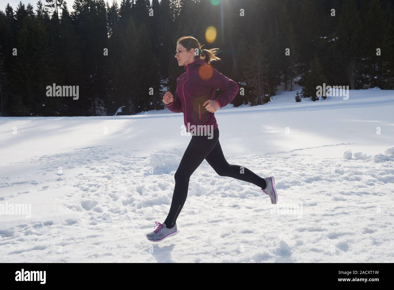 Yougn woman jogging en forêt sur la neige en plein air Banque D'Images