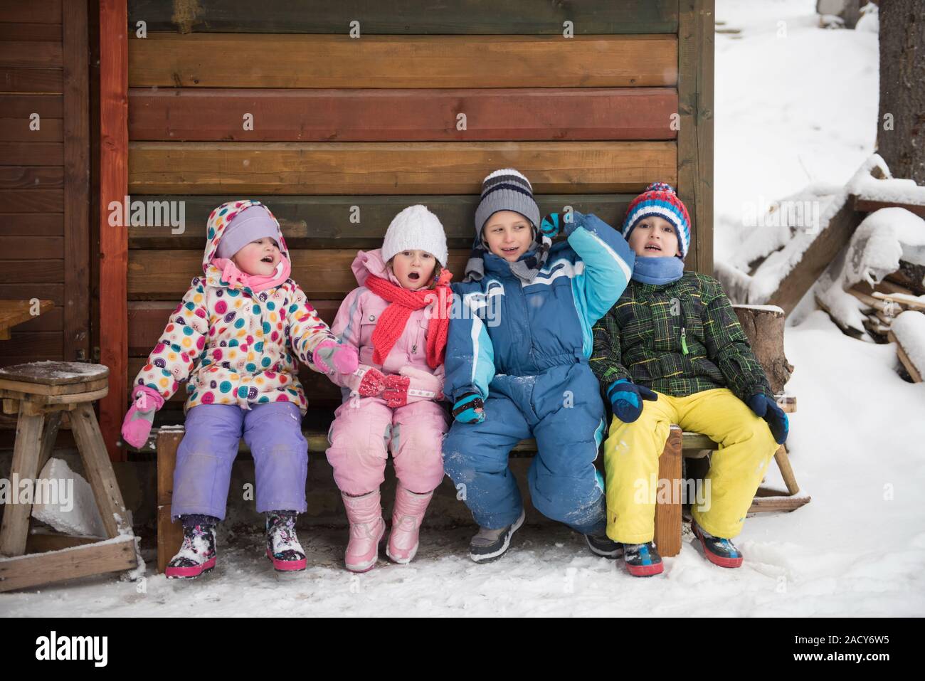 Groupe de petits enfants assis en face de chalet en bois Banque D'Images