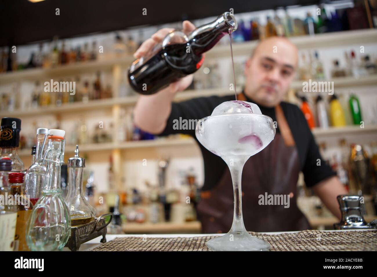 Barman est de verser le vin dans le verre avec de la glace géant, image grand-angle. Banque D'Images