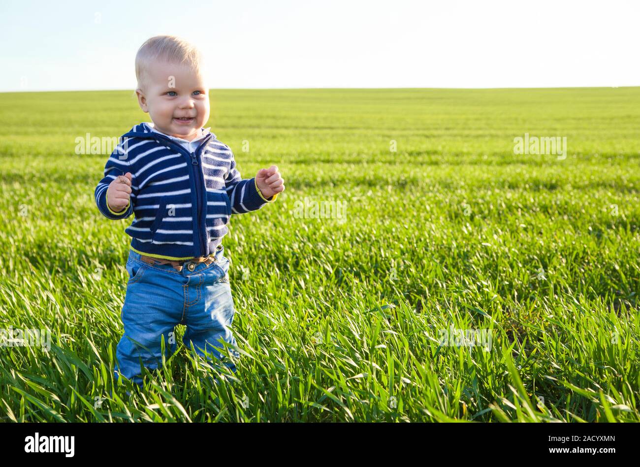 Magnifique petit garçon debout dans l'herbe verte Banque D'Images