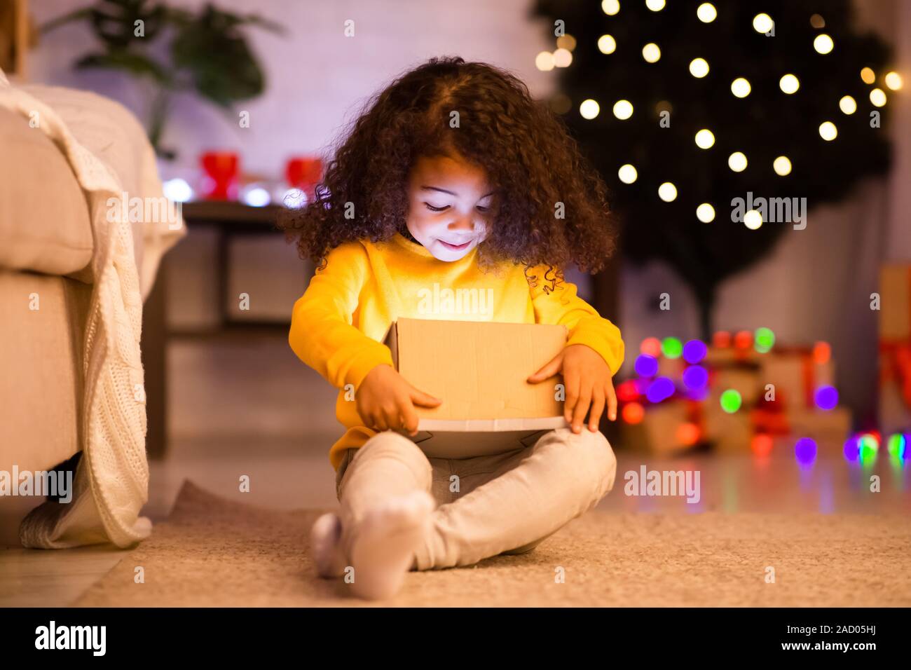 Surpris de l'ouverture de l'enfant Noël lumineux afro don Banque D'Images
