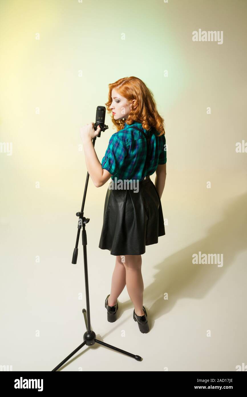 Chanteur élégant avec curly red hair holding mic Banque D'Images