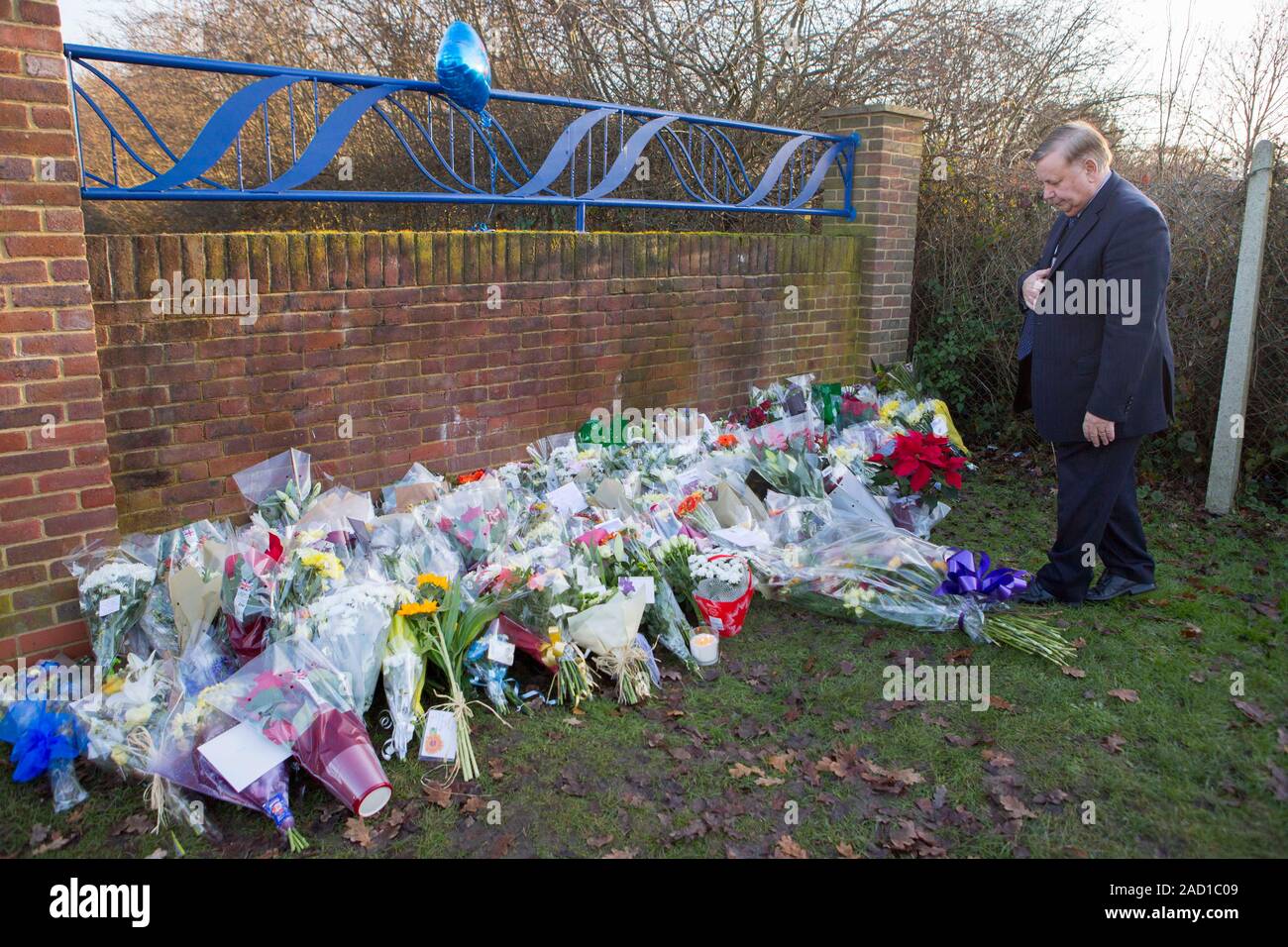 Président d'Epping Forest District Council Le conseiller Richard Bassett, examine les bouquets à gauche à l'entrée de Debden Park High School, à Willingale Road, Loughton, Essex, en tant qu'une enquête pour meurtre a été lancé après qu'un jeune garçon de 12 ans qui a été fauché alors qu'il quittait l'école avec ses amis dans ce que la police croit qu'on a délibérément hit-and-run crash. PA Photo. Photo date : mardi 3 décembre 2019. L'élève, nommé localement comme Harley Watson, subissent des blessures mortelles après une voiture hurtled dans une foule de jeunes en dehors de l'école, le lundi après-midi. Deux garçons de 15 ans, un 13-y Banque D'Images
