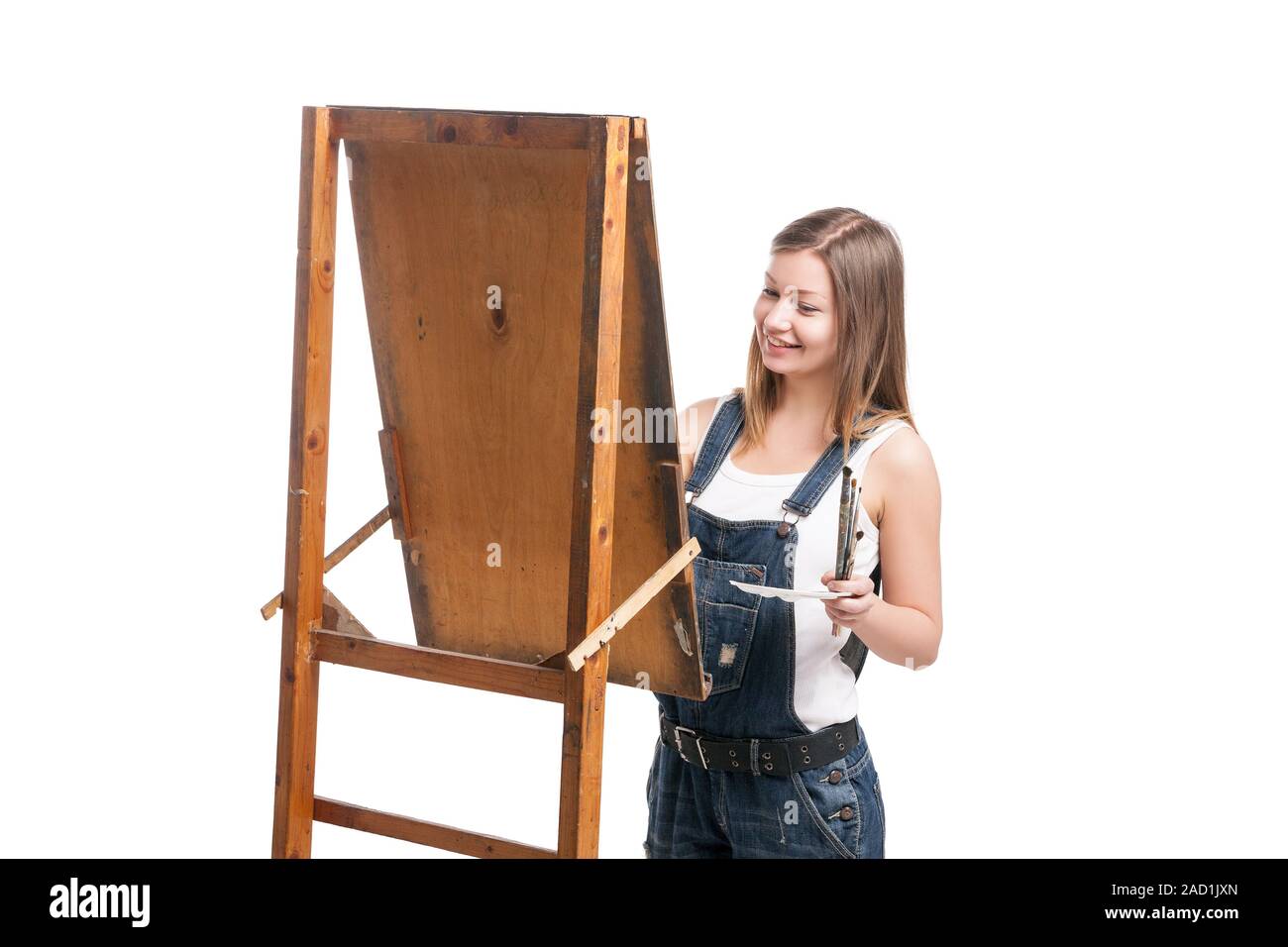 Young smiling woman painter avec paintbrush standing at easel Banque D'Images