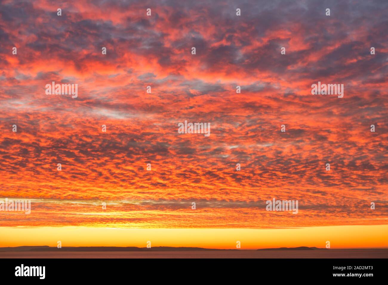 Lever et coucher du soleil orange Fiery sky avec des maquereaux la formation des nuages sur la mer. Banque D'Images
