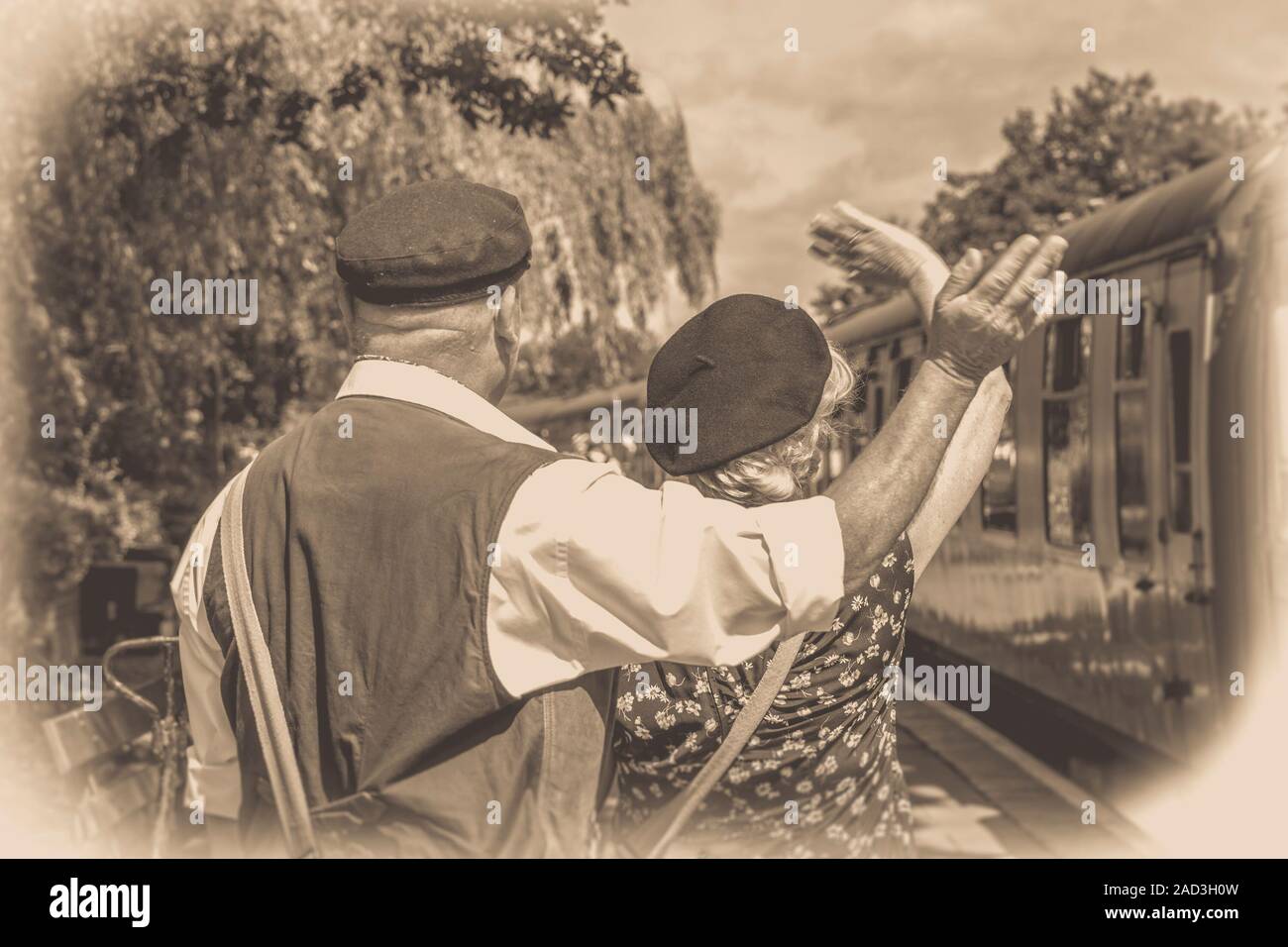 Arrière blanc noir vue arrière du Royaume-Uni couple, robe des années 1940, sur plate-forme, Severn Valley Railway station de la seconde guerre mondiale en compagnie de Au revoir à des amis sur le train à vapeur d'époque. Banque D'Images
