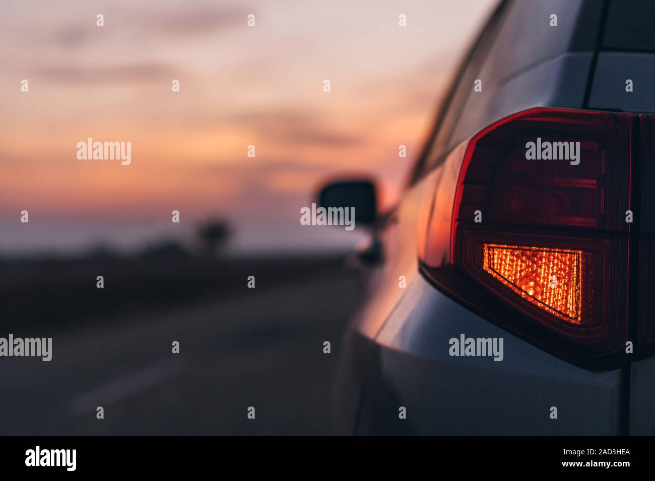 Feu stop arrière voiture dans le coucher du soleil, selective focus droit du véhicule clignotent dans le noir Banque D'Images