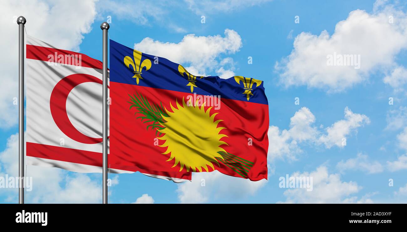 Chypre du Nord et la Guadeloupe drapeaux dans le vent contre ciel bleu nuageux blanc ensemble. Concept de diplomatie, de relations internationales. Banque D'Images