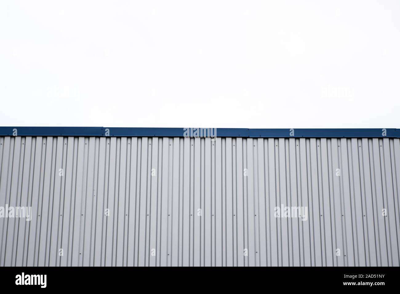 Plaques ondulées métalliques sur un bâtiment avec un bleu metal coins. Toit ondulé en aluminium blanc pour mur ou contre feuilles ciel nuageux sur l'arrière-plan Banque D'Images
