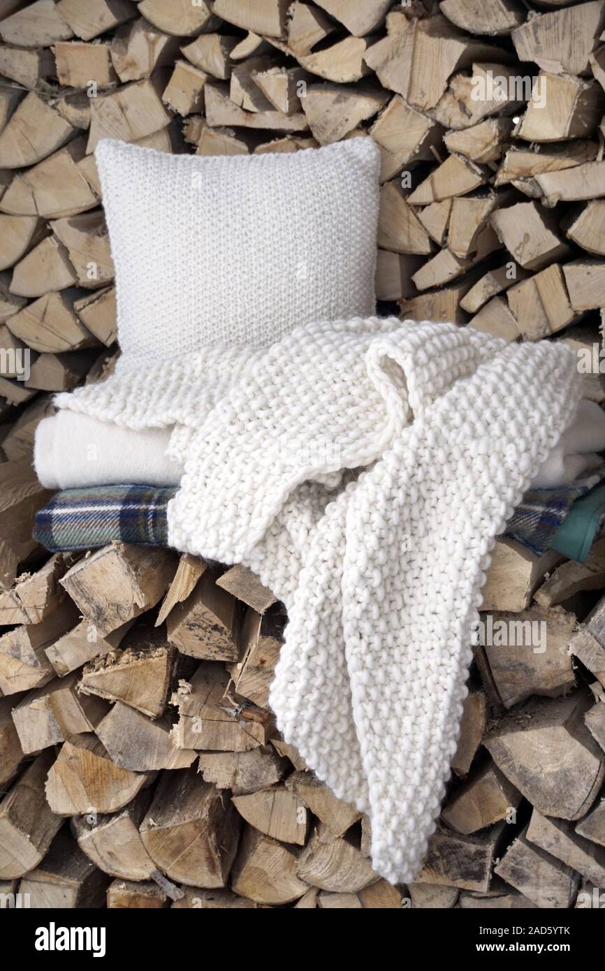 Accessoires pour un pique-nique d'hiver (couverture de pique-nique à carreaux laine, tapis blanc, blanc laine tricot chunky couverture et un coussin en tricot blanc) allongé sur un tas de Banque D'Images