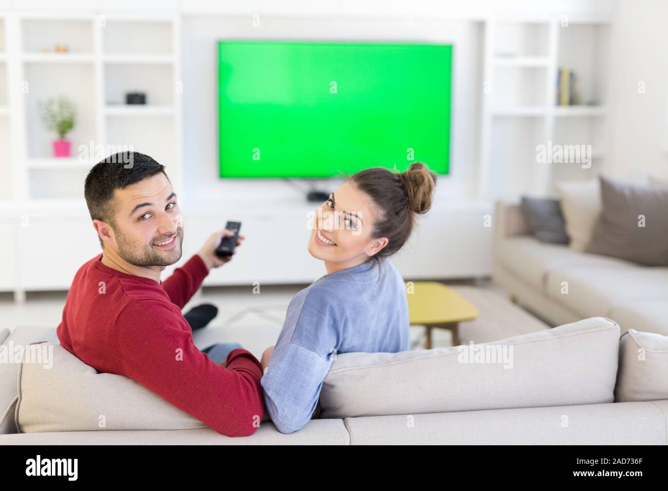 Jeune couple sur le canapé à regarder la télévision Banque D'Images